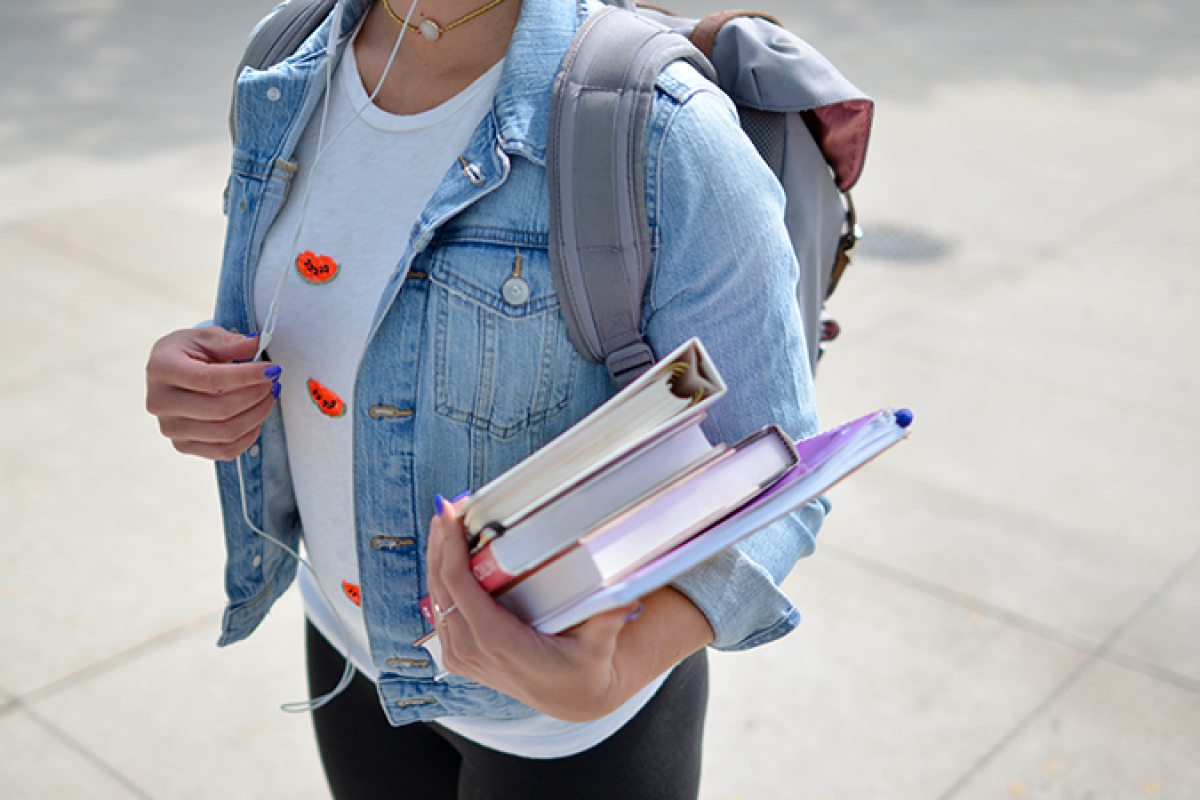 Student carrying books and wearing a backpack