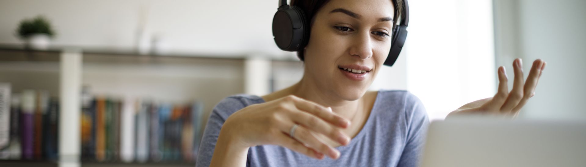 woman wearing headphones sitting in front of a laptop gesturing with her hands