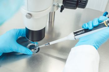 gloved hands using a pipette in a lab